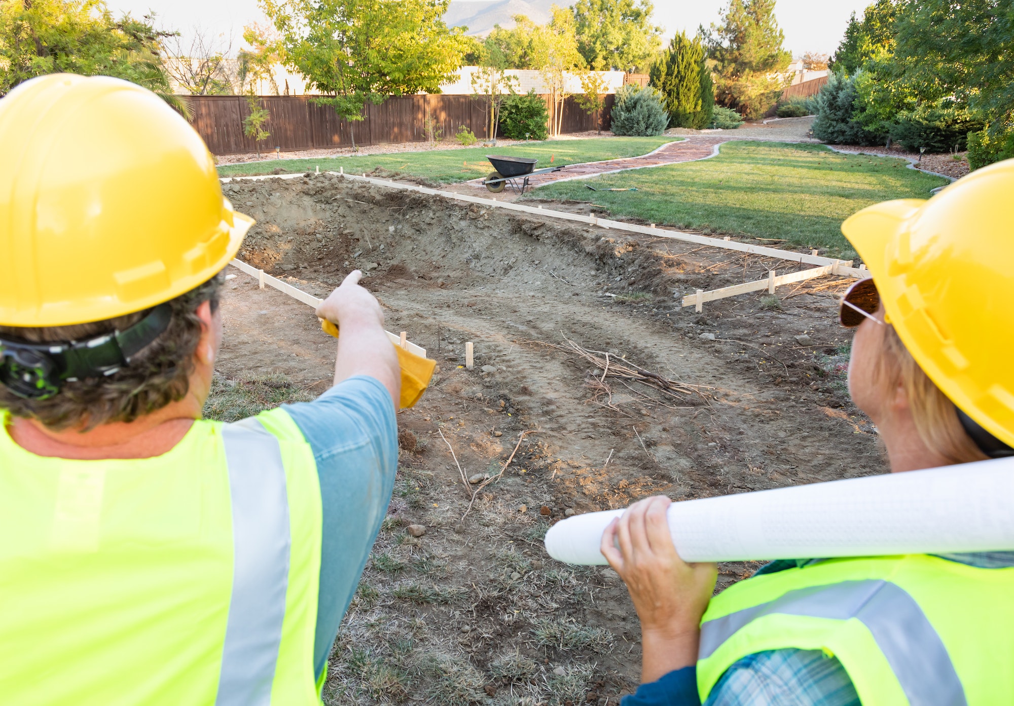 Male and Female Workers Overlooking Pool Construction Site